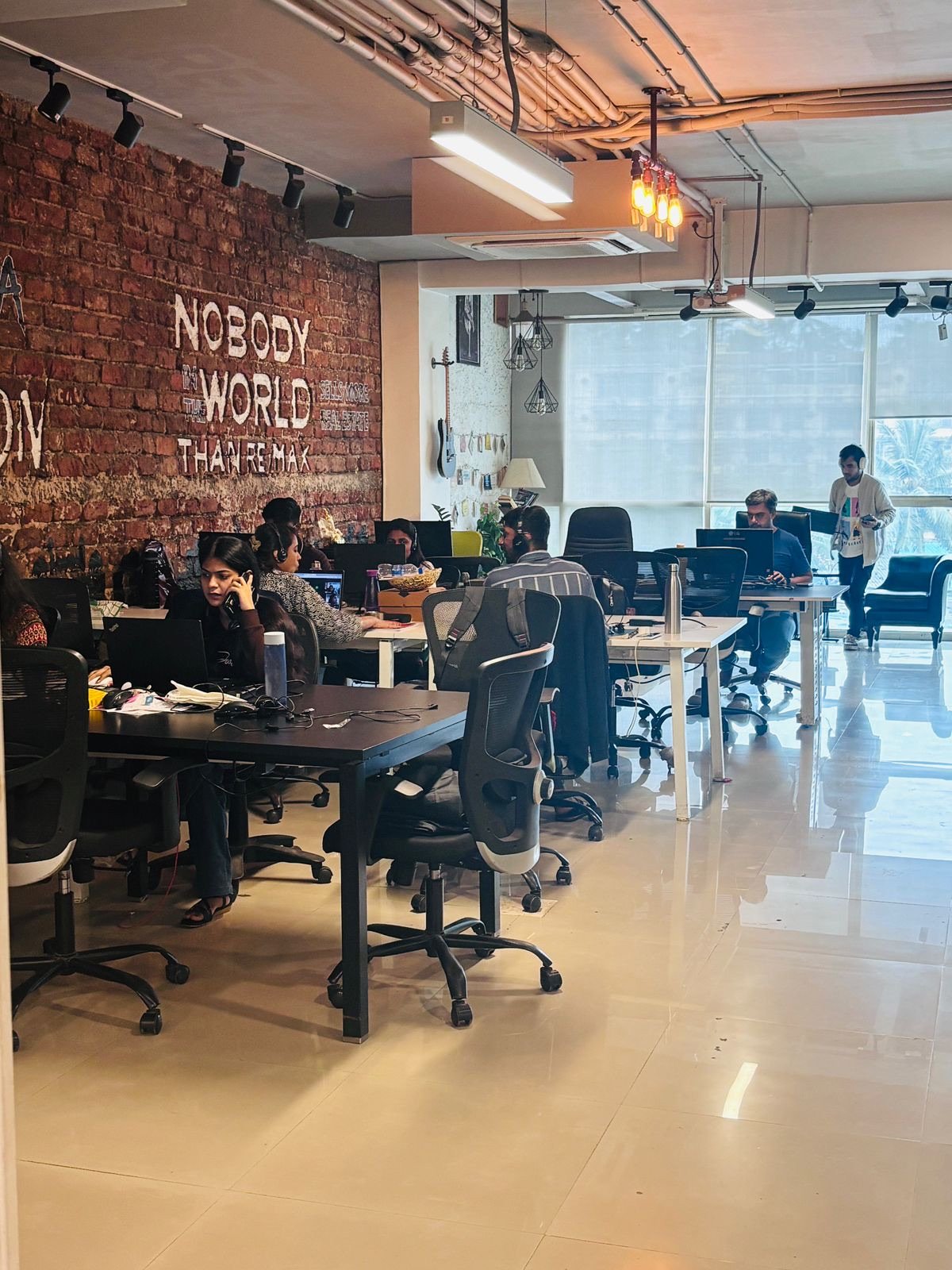 Members working at DivineHub co-working space with brick feature wall